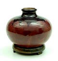 Donkerrood geglazuurde aardewerk vaas met stervormig donker glazuur aan bovenzijde op goud-brons geglazuurde ronde aardewerk voet ontwerp uitvoering Pieter Groeneveldt / Voorschoten 1927-1945 