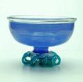 Vrij geblazen helderglazen Unica kom aan de binnenzijde gedecoreerd met spiraal van blauwe glasdraden met helderglazen tagliatelle -gevormde aangezette voet waarvan de binnenzijde gedecoreerd is met een turquoise laag ontwerp A.D.Copier 1981 uitvoering Lino Tagliapietra Murano / Italië 