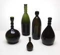  Set van 5 flessen ontwerp Jac.Jongert in 1920 voor Paq.Port van de firma Wed.G.Oud Pzn en Co / Purmerend uitvoering N.V.United Glassworks Schiedam Hoogtes 29,6 / 24,8 / 22 / 21,7 / 10,3 cm 