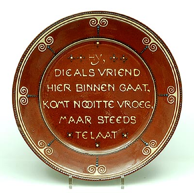 Earthenware wallplate with geringeloorde tube-lining decoration and text Hij die als vriend hier binnen gaat komt nooit te vroeg maar steeds te laat design C.J.van der Hoef executed by VH Amstelhoek / the Netherlands 1904-'10 