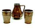 Steengoed Coppper Ware schenkkan met twee bekers met gesimuleerde koperen klinknagels allen met 1e geh zilveren rand ontwerp uitvoering Doulton Lambeth Silicon 1893 / Engeland Copper Ware werd geïntroduceerd in de tweede helft van de 19e eeuw door Doulton Lambeth Silicon en gaf de Arts and Crafts invloed van dat moment weer 