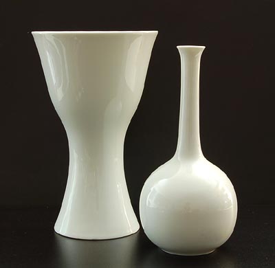 Twee wit geglazuurde porseleinen vazen ontwerp Wilhelm Wagenfeld 1972 uitvoering Fürstenberg / Duitsland Resp hoogtes 21,9 en 23,8 cm 