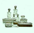 Een Art Nouveau zilveren geslepen kristallen toilet garniture gedreven en geciseleerd zilver ieder object met een andere bloem of plant gemonteerd op kristal geslepen met geometrische motieven bevat vier flacons met klepdeksel en glazen stoppen vier dozen met deksels en drie borstels ontwerp Phillipe Wolfers uitvoering Wolfers Frères België / Brussel ca.1900 
